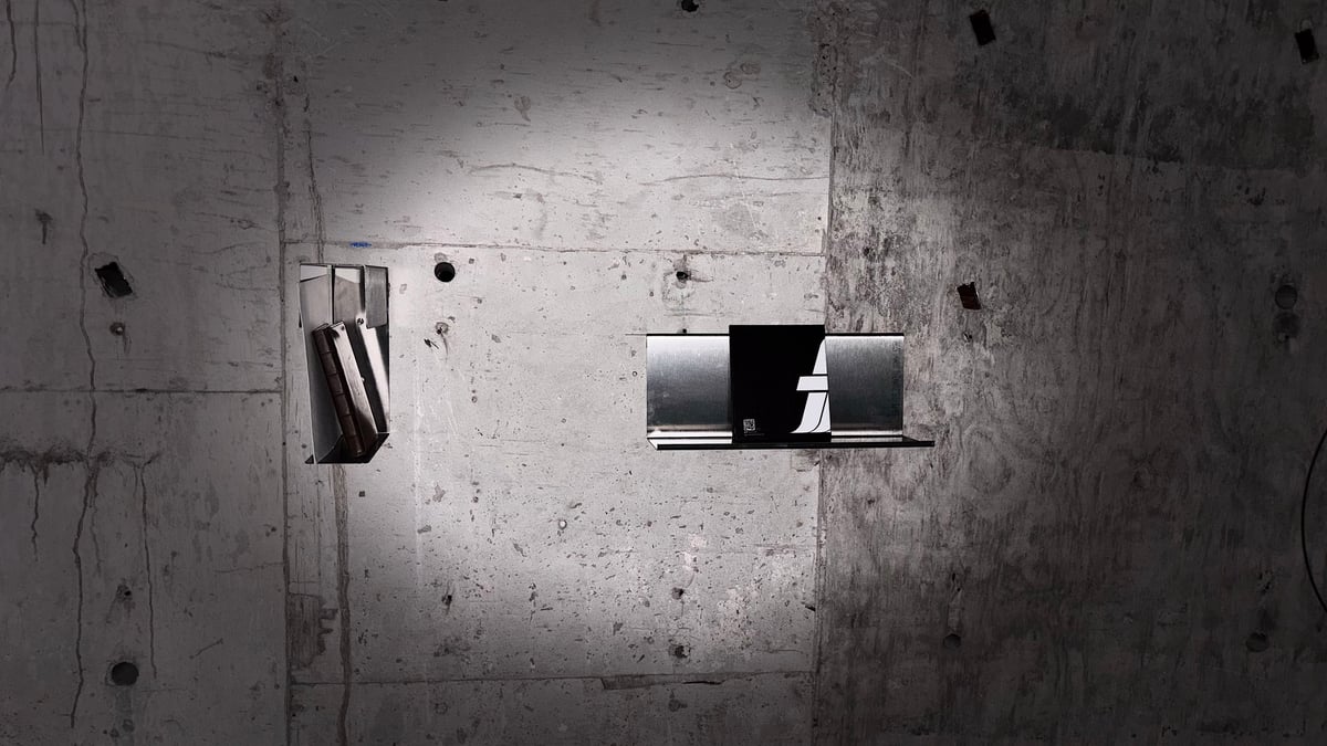 A small light switch and outlet mounted on a weathered concrete wall with visible stains and wear marks