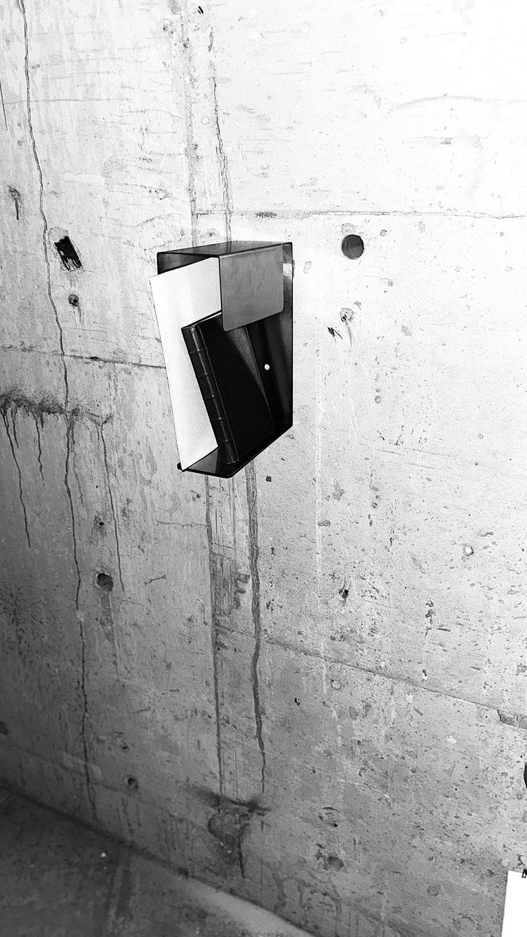 Black and white modern light switch mounted on a rough concrete wall with visible wear and stains